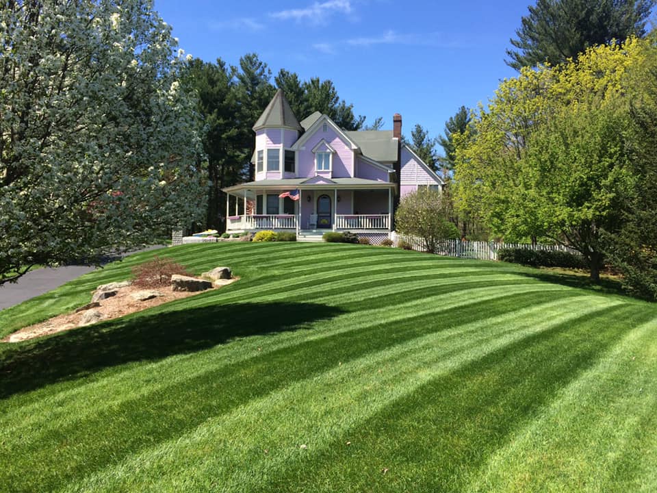 Victorian-style house with a large front lawn featuring bold mowing stripes.