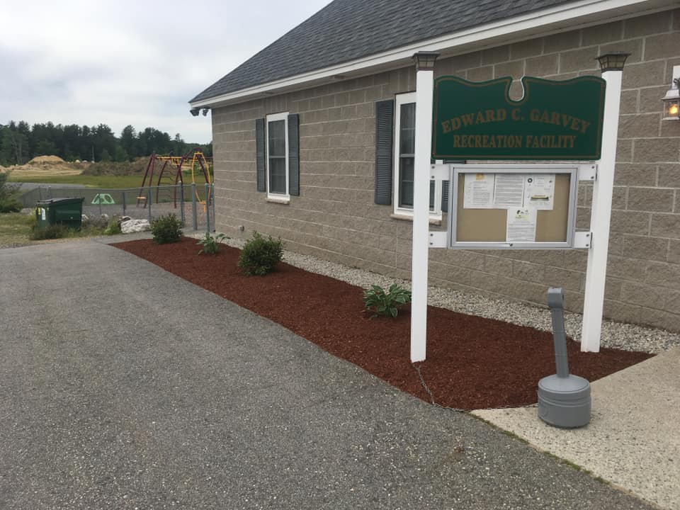 Commercial building with fresh mulch landscaping and a white information sign in front.