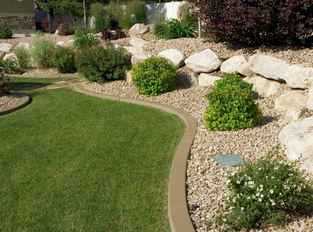 Landscaped yard with curved lawn edge, decorative rocks, shrubs, and boulders.