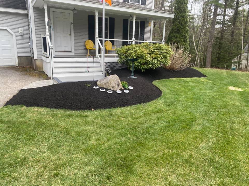 Front yard with fresh black mulch, decorative rock, and a well-kept lawn in Sandown, NH.